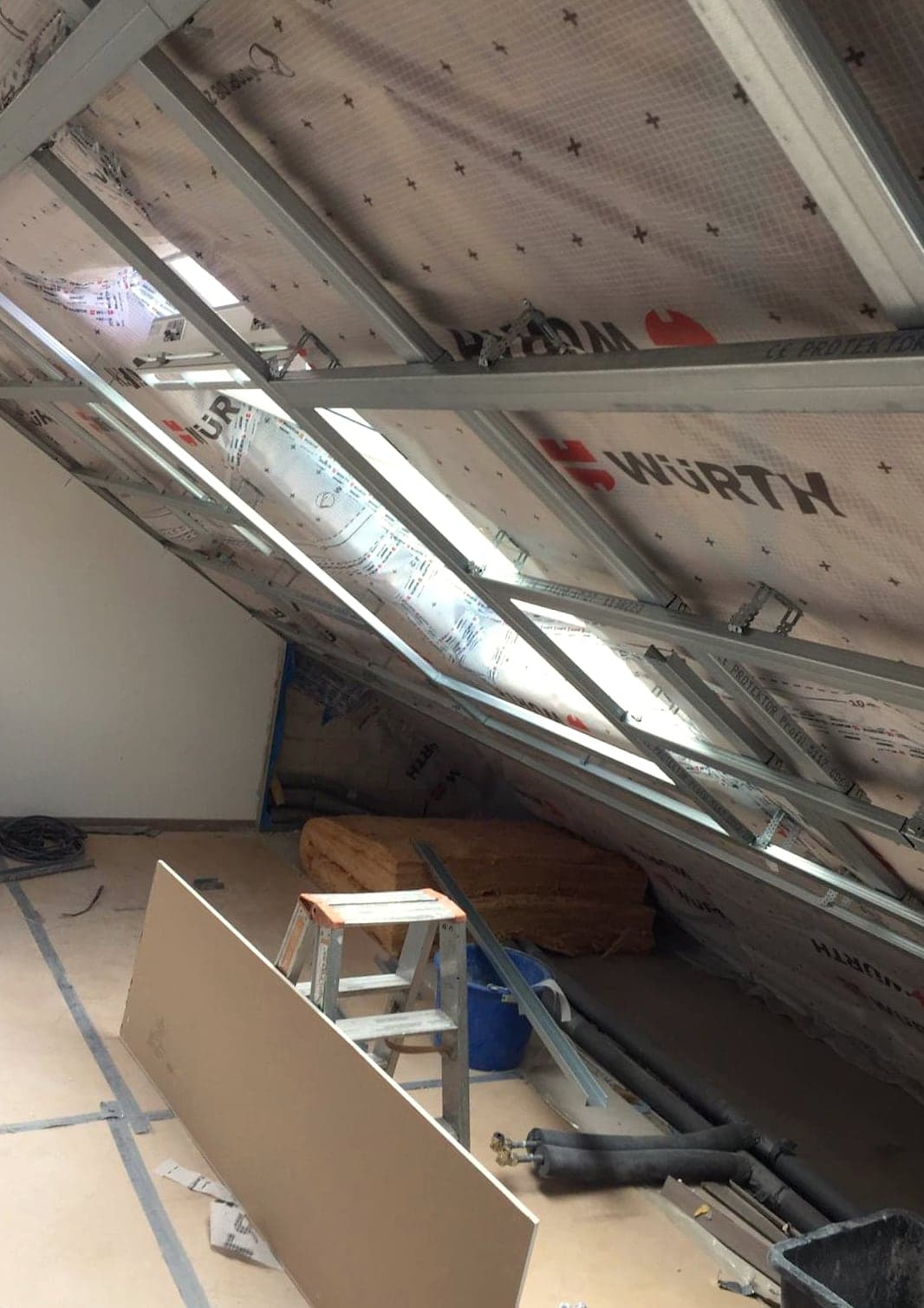 Dachschräge im Ausbau: Unterspannbahn zwischen den Sparren, Metallprofile gesetzt, erste Platte angestellt